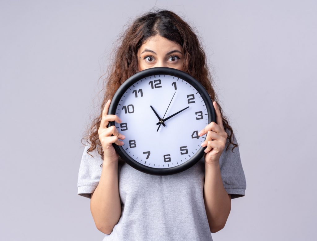 femme qui se cache derrière une horloge