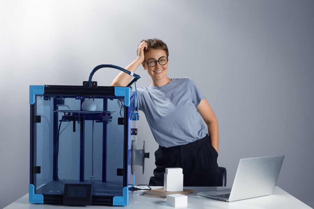 femme qui s'appui sur une imprimante 3D