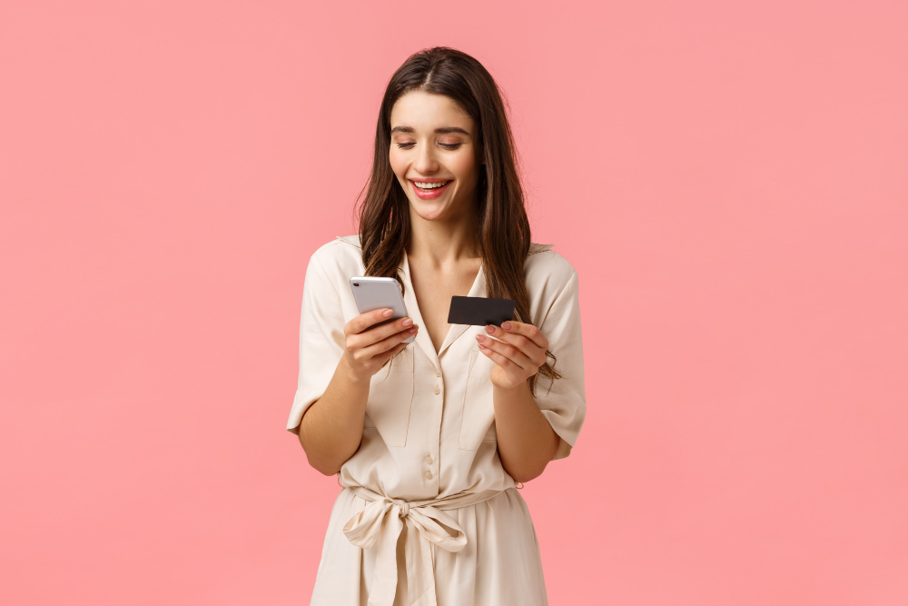 femme sur son telephone avec une carte de crédit