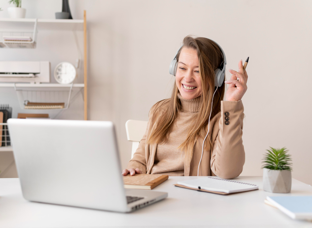 une jeune femme suivant une formation en ligne en rigolant devant son ordinateur